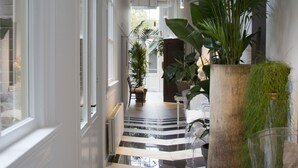 A hallway with a checkered floor, white walls, and large windows. - Boutiquehotel Staats (Haarlem)