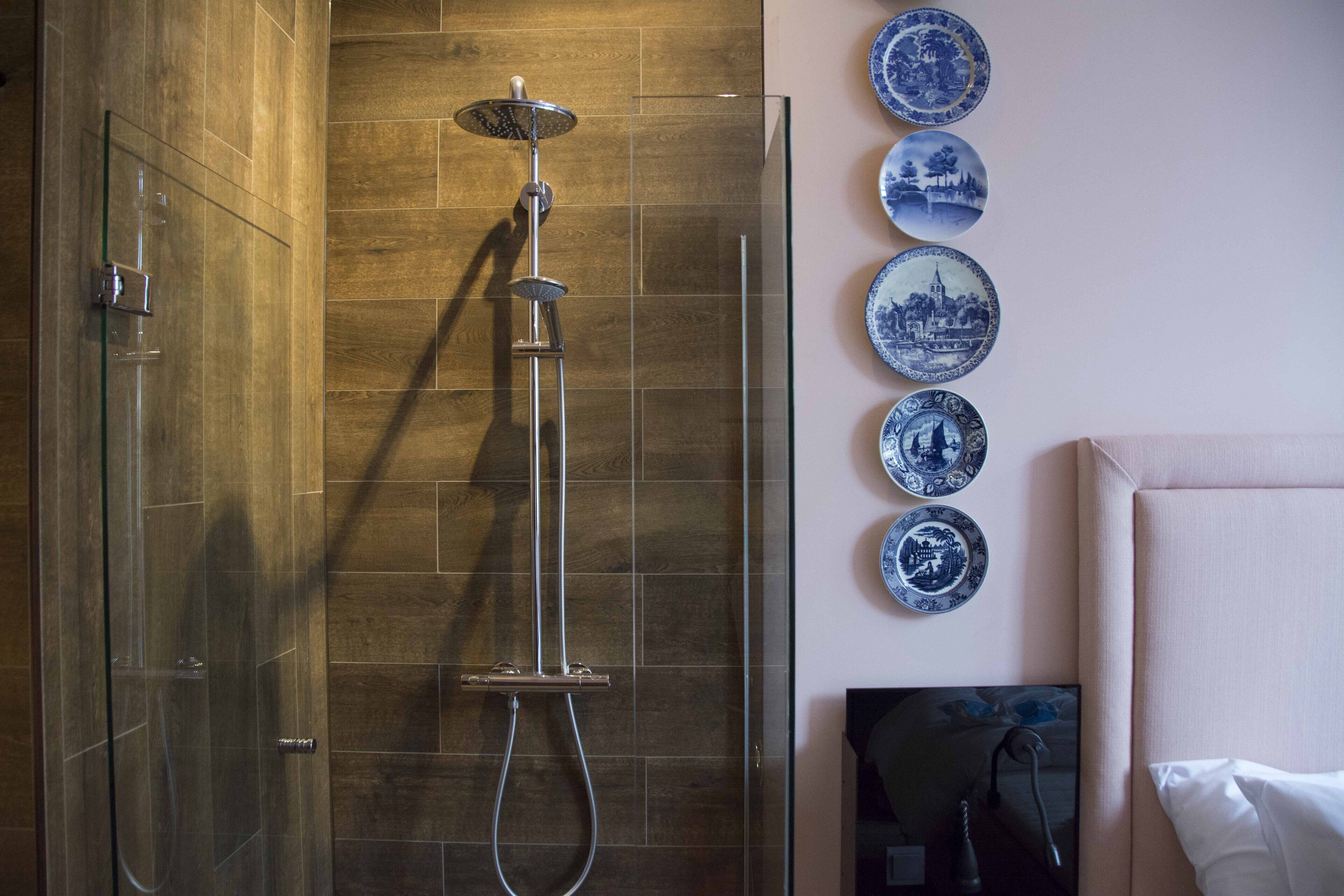 Un baño con ducha de vidrio, baldosas de madera y televisor montado en la pared.