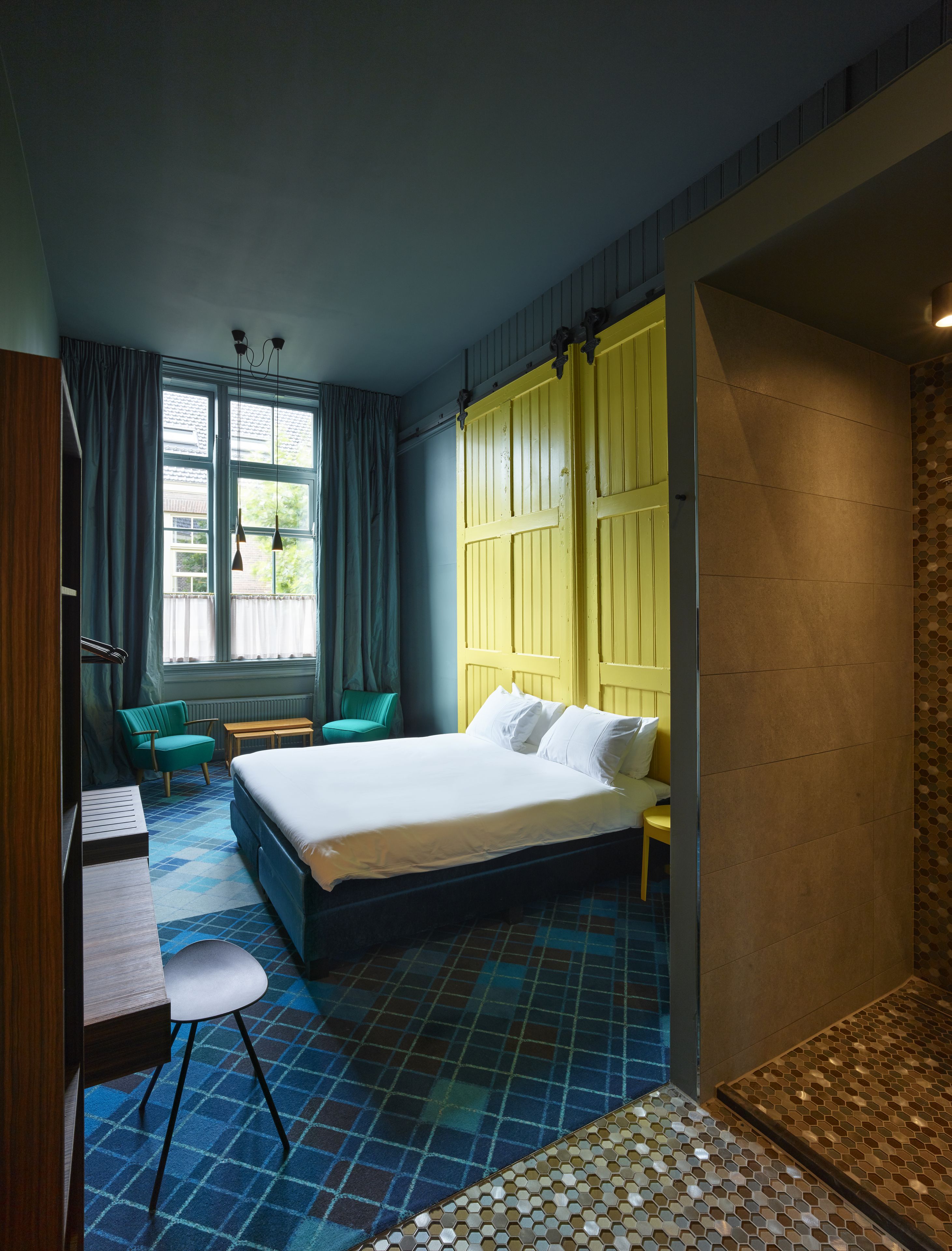 Ein Hotelzimmer mit Bett, Schreibtisch, Stuhl und einem fensterbepflegten Fenster.