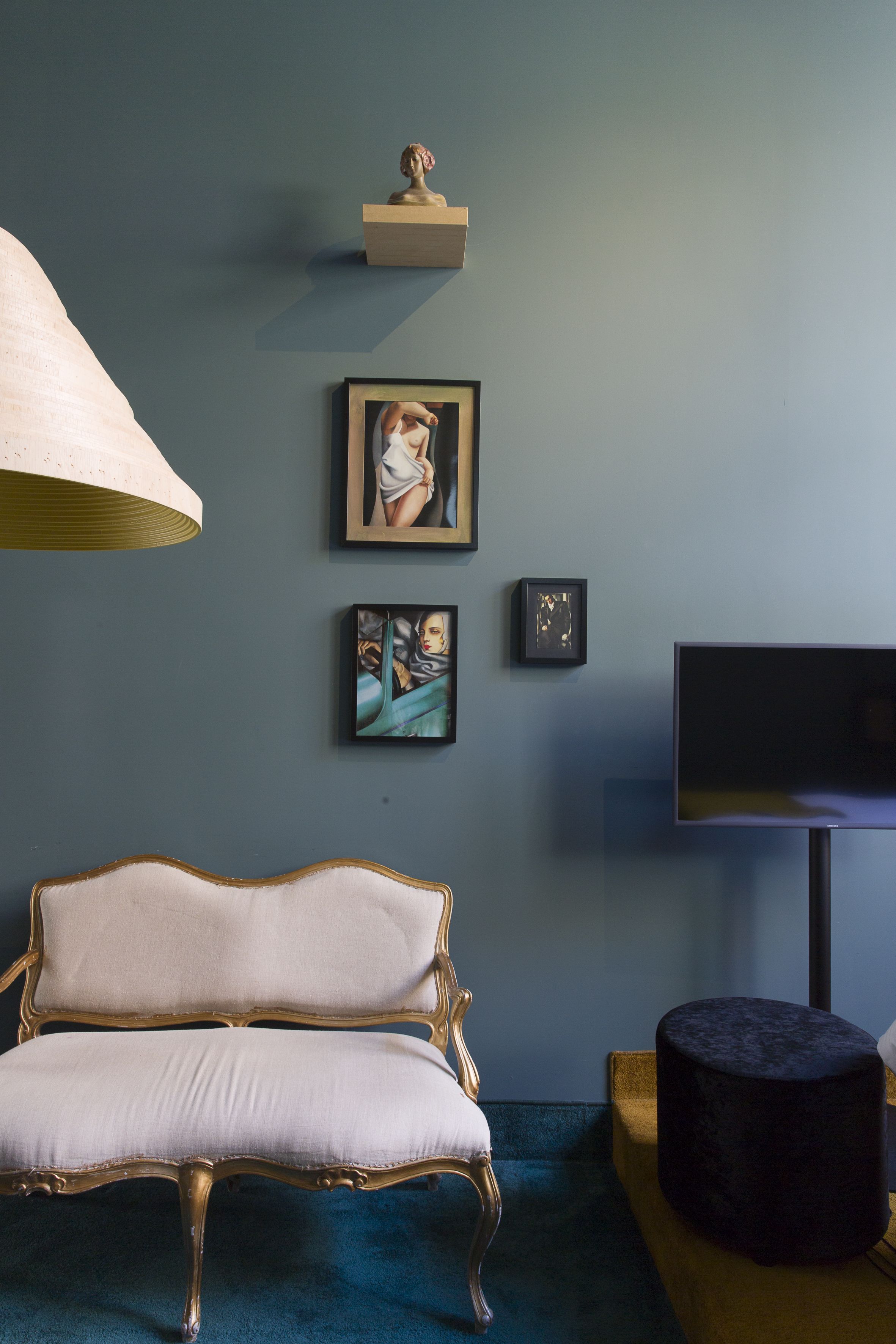 A room with a vintage-style sofa, a flat-screen TV, and artwork on the wall.