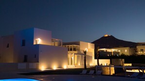 A modern hotel with a pool area, lounge chairs, and a mountain view. - Camarò Favignana (Favignana)
