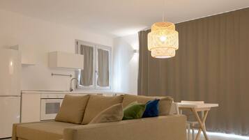 Ein modernes Wohnzimmer mit einem beigen Sofa, einem kleinen weißen Tisch und einer Pendelleuchte.