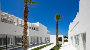 A modern building with white exterior walls, large glass doors, and a clear blue sky. - Camarò Favignana (Favignana)