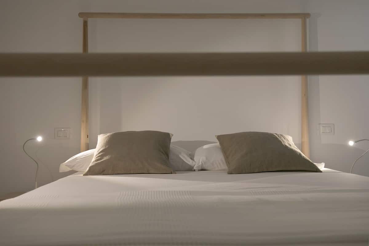 A bed with a wooden headboard, two pillows, and bedside lamps.