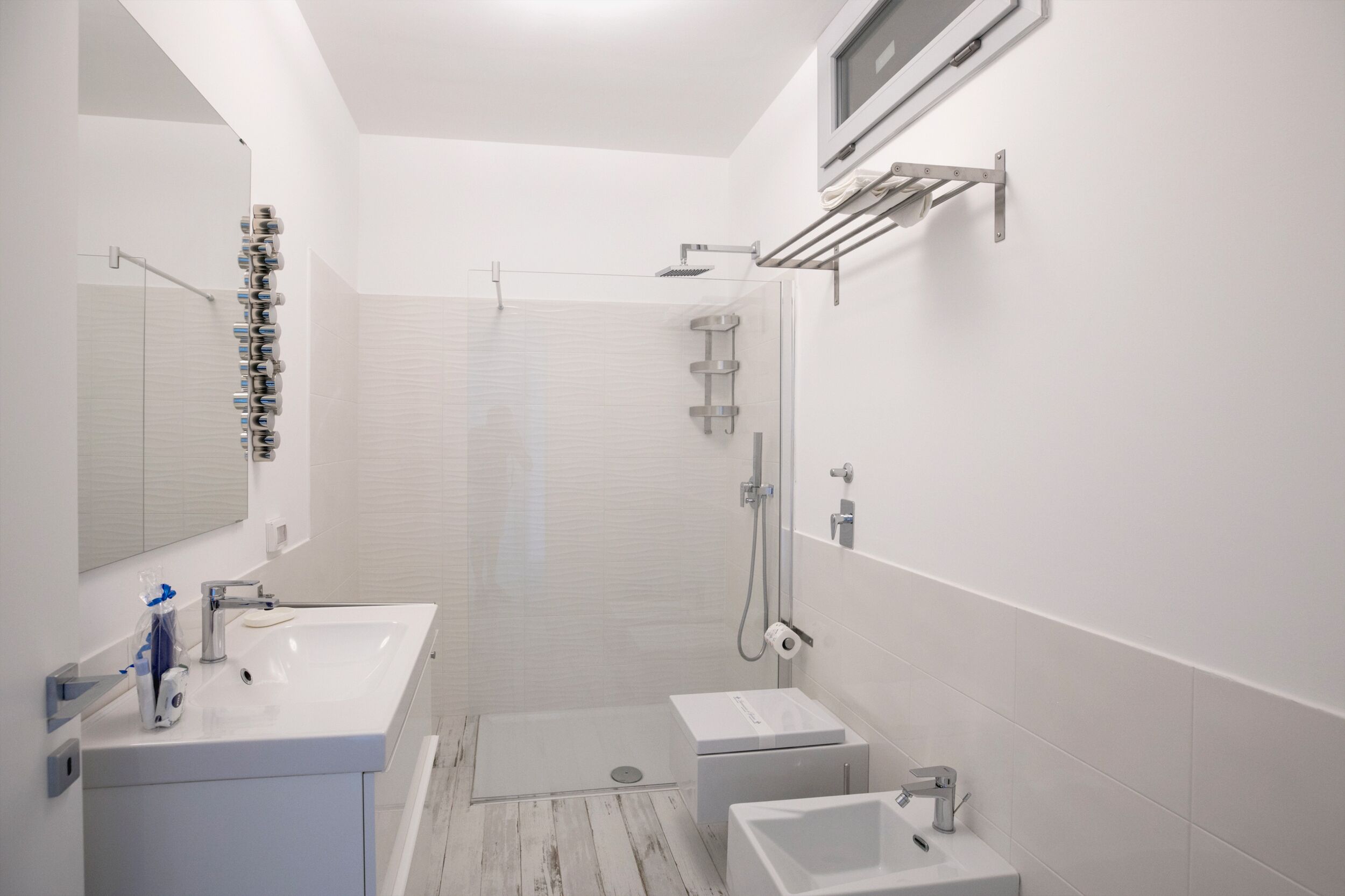 Ein modernes Badezimmer mit einem großen Waschbecken, einem Spiegel, einer Dusche und einer Toilette.