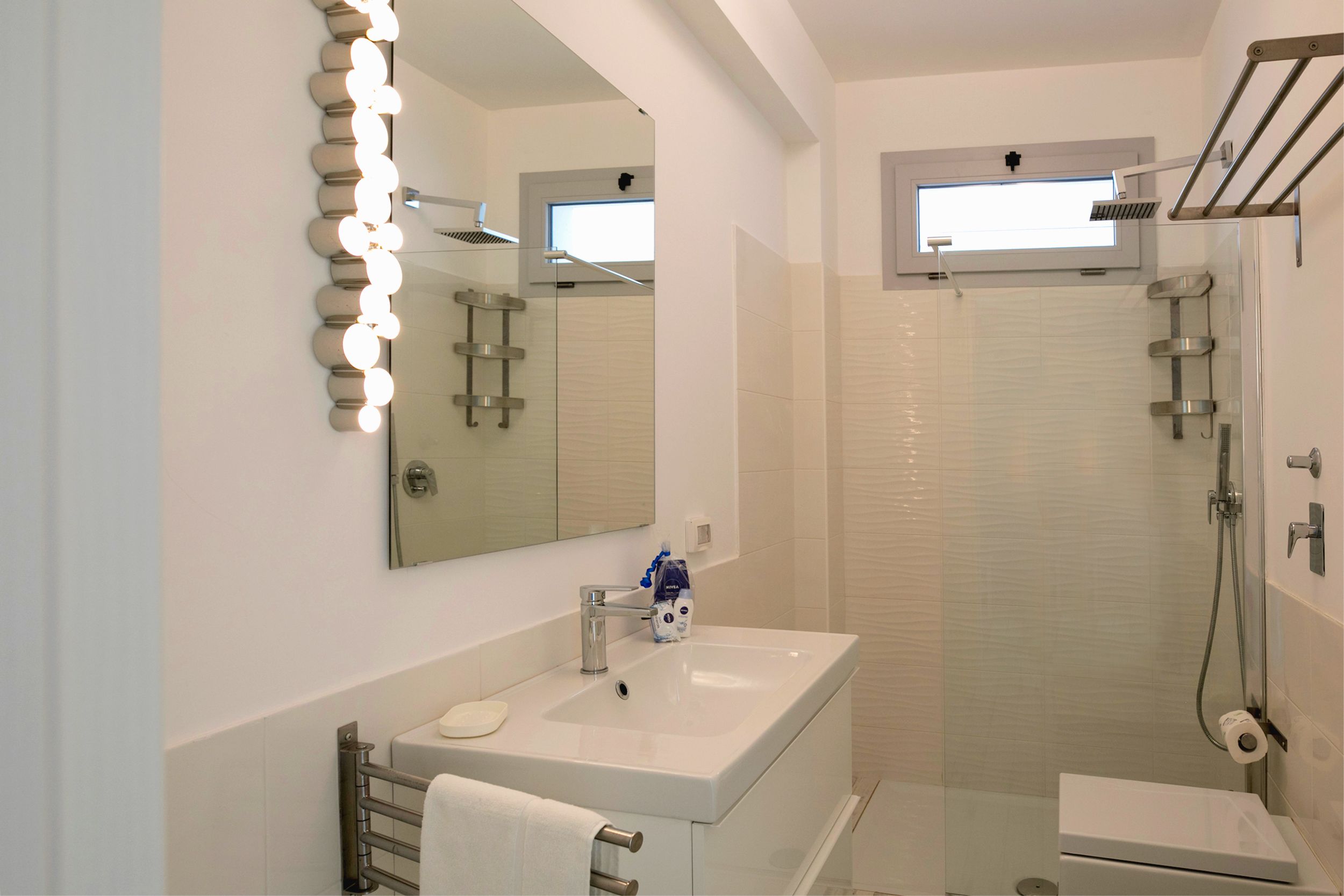 Un bagno moderno con lavabo, specchio e doccia.