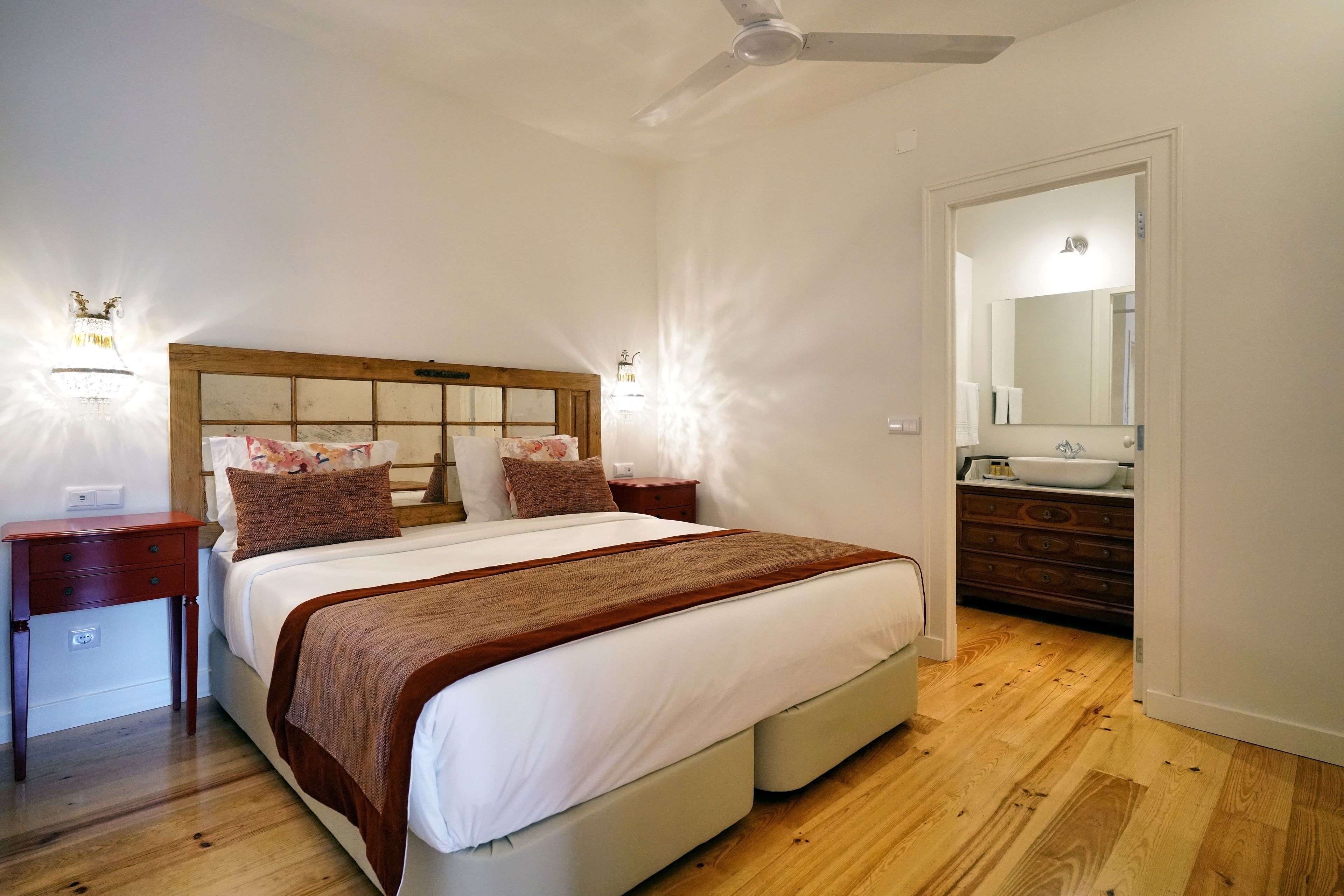 A bedroom with a large bed, wooden headboard, bedside tables, and a nightstand.