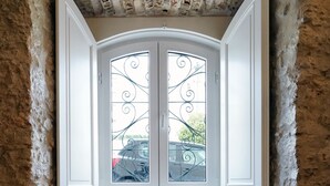 Unos escalones de piedra conducen a una puerta con una reja metálica decorativa, incrustada en una pared de piedra rústica.
