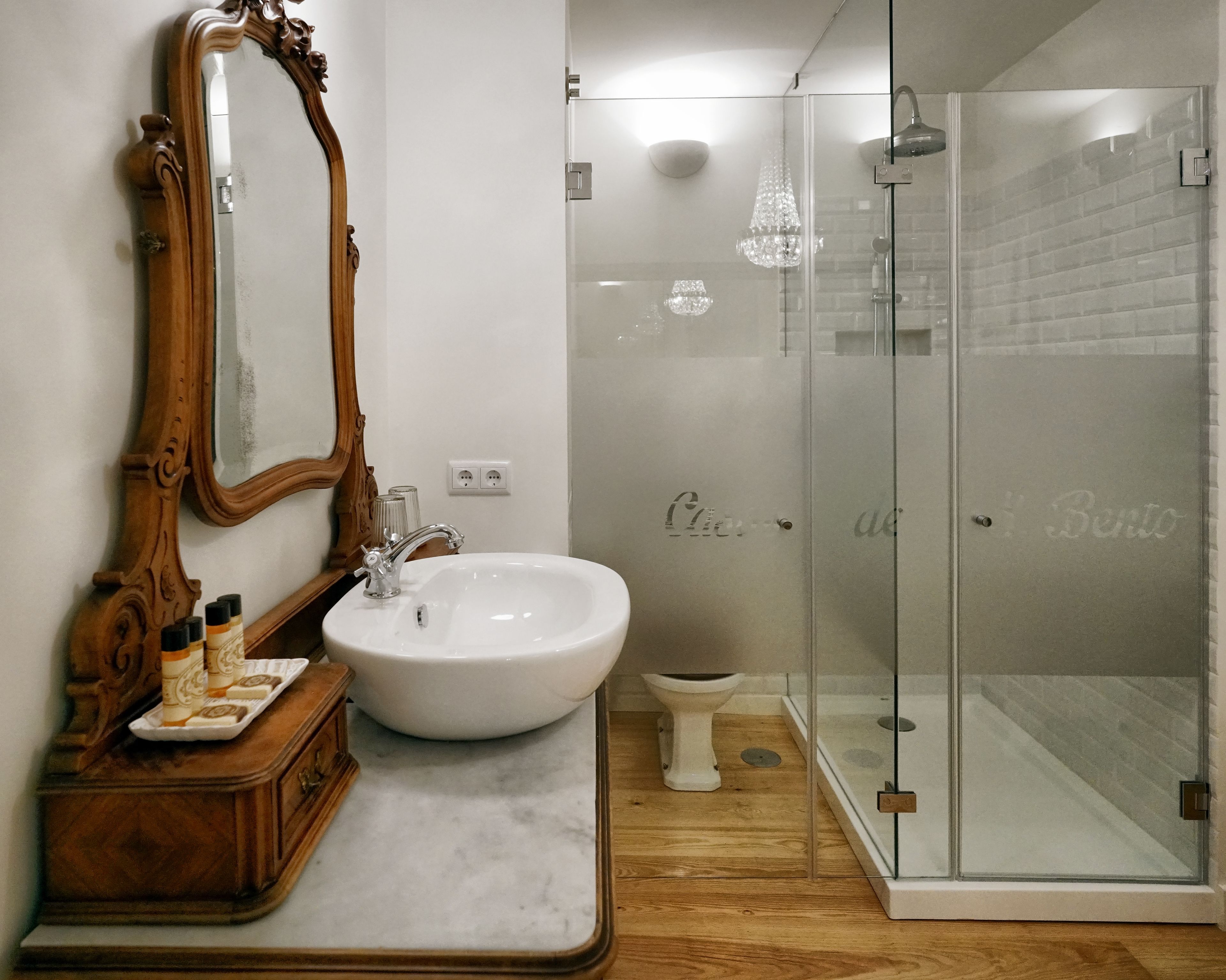 A bathroom with a wooden vanity, a white sink, and a glass-enclosed shower.