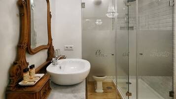 A bathroom with a wooden vanity, a white sink, and a glass-enclosed shower.