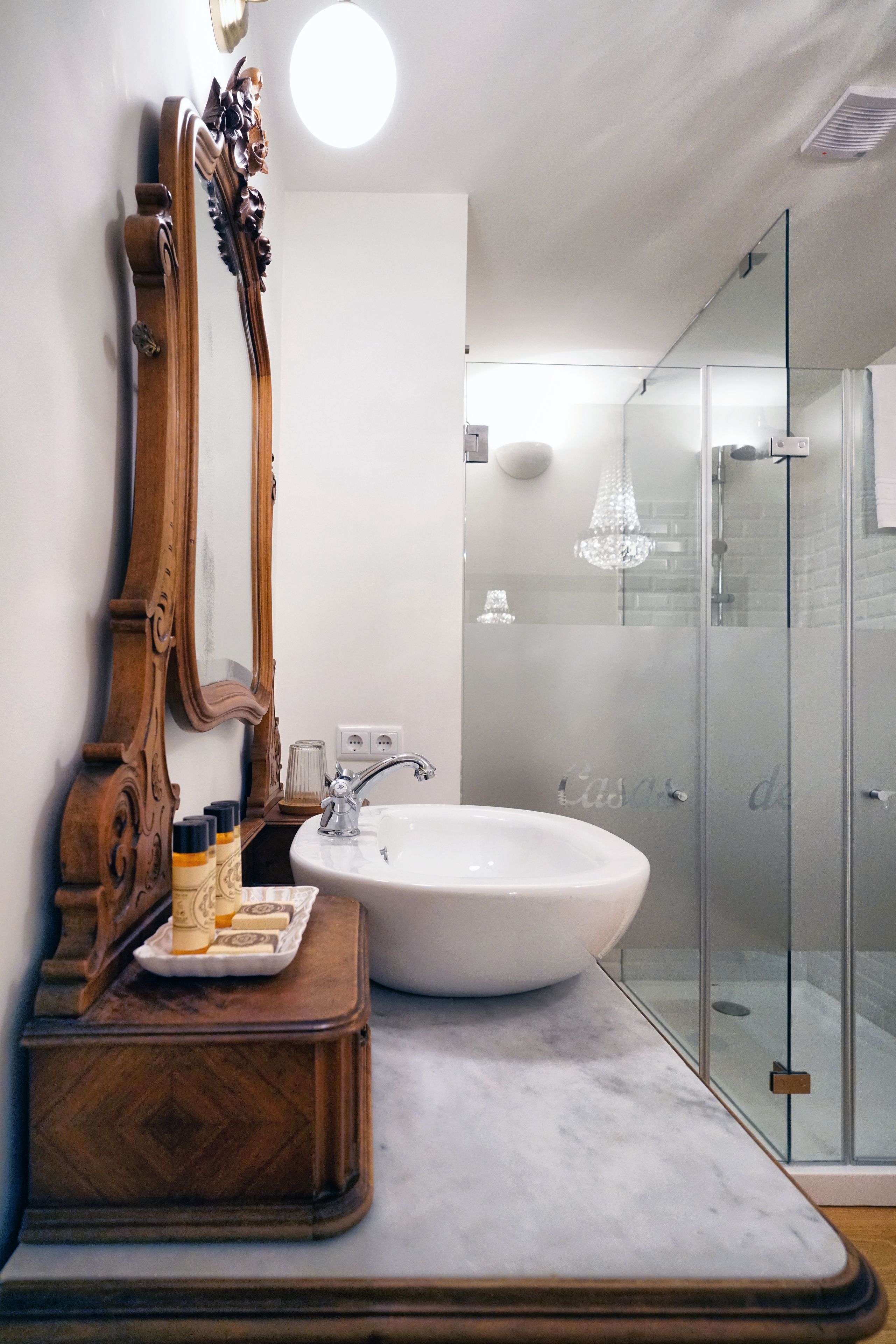 Un bagno con lavabo in marmo, mobile contenitore in legno e uno specchio grande.