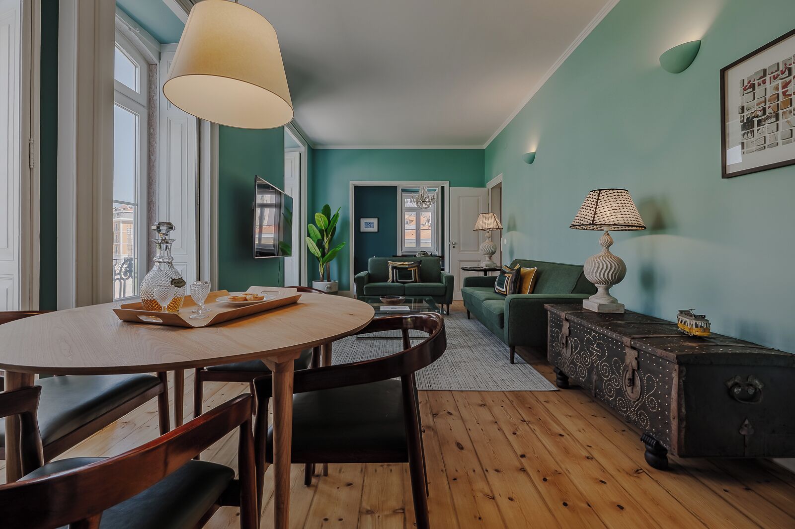 Un salon chaleureux avec un canapé vert, une table à manger avec des chaises et une table basse.
