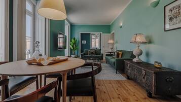 Un salon chaleureux avec un canapé vert, une table à manger avec des chaises et une table basse.