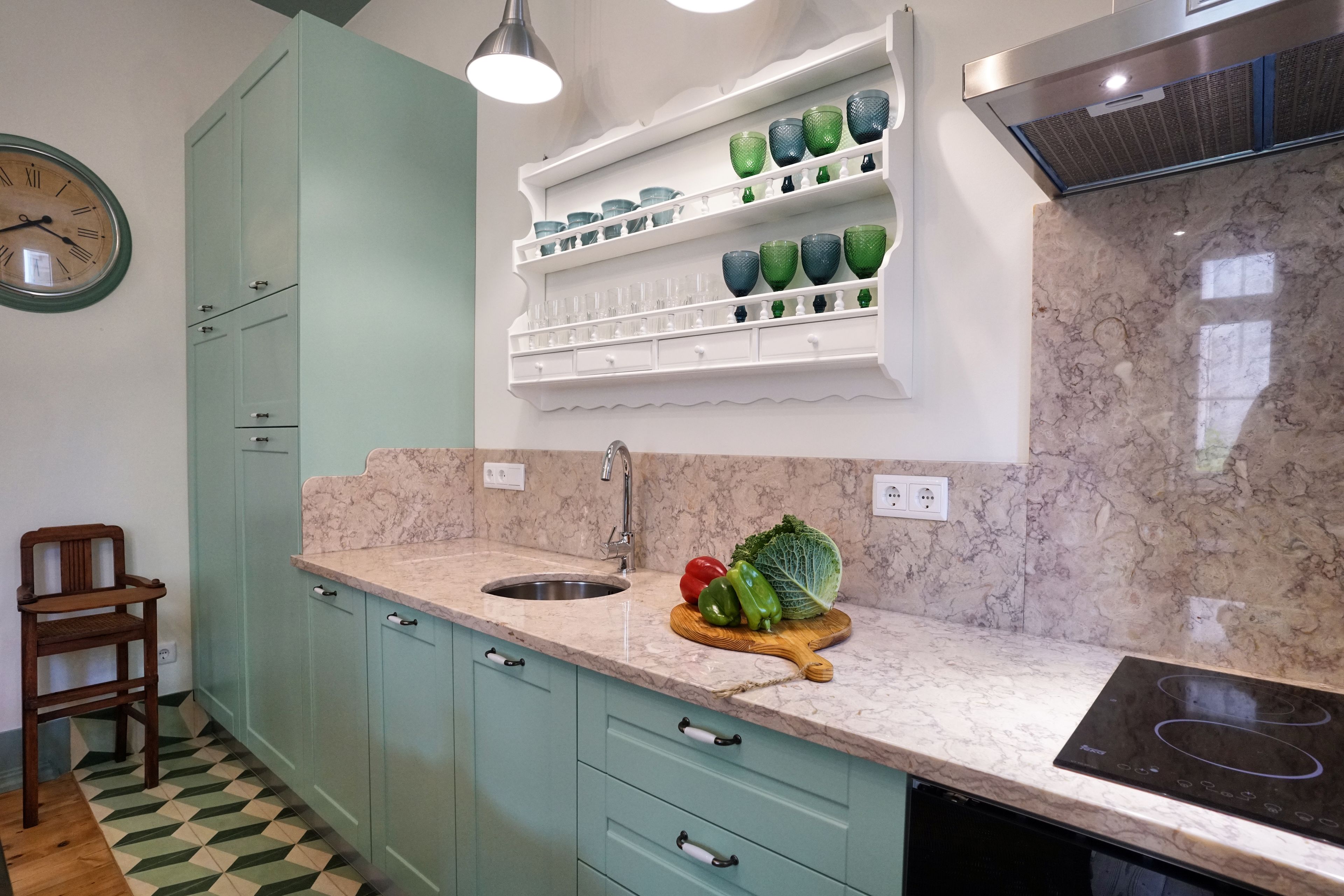 A kitchen with teal cabinets, a marble countertop, a sink, and a stove.