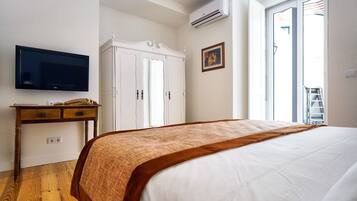 A bedroom with a bed, a TV, a wardrobe, and a window.