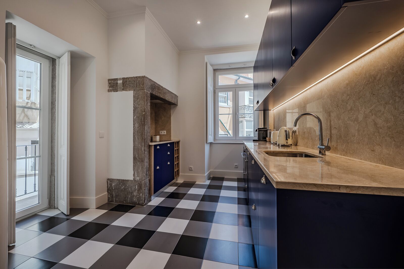A modern kitchen with a checkered floor, a built-in oven, and a large window.