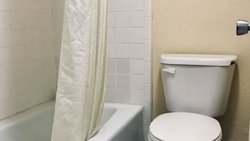 A bathroom with a bathtub, toilet, and a shower curtain.