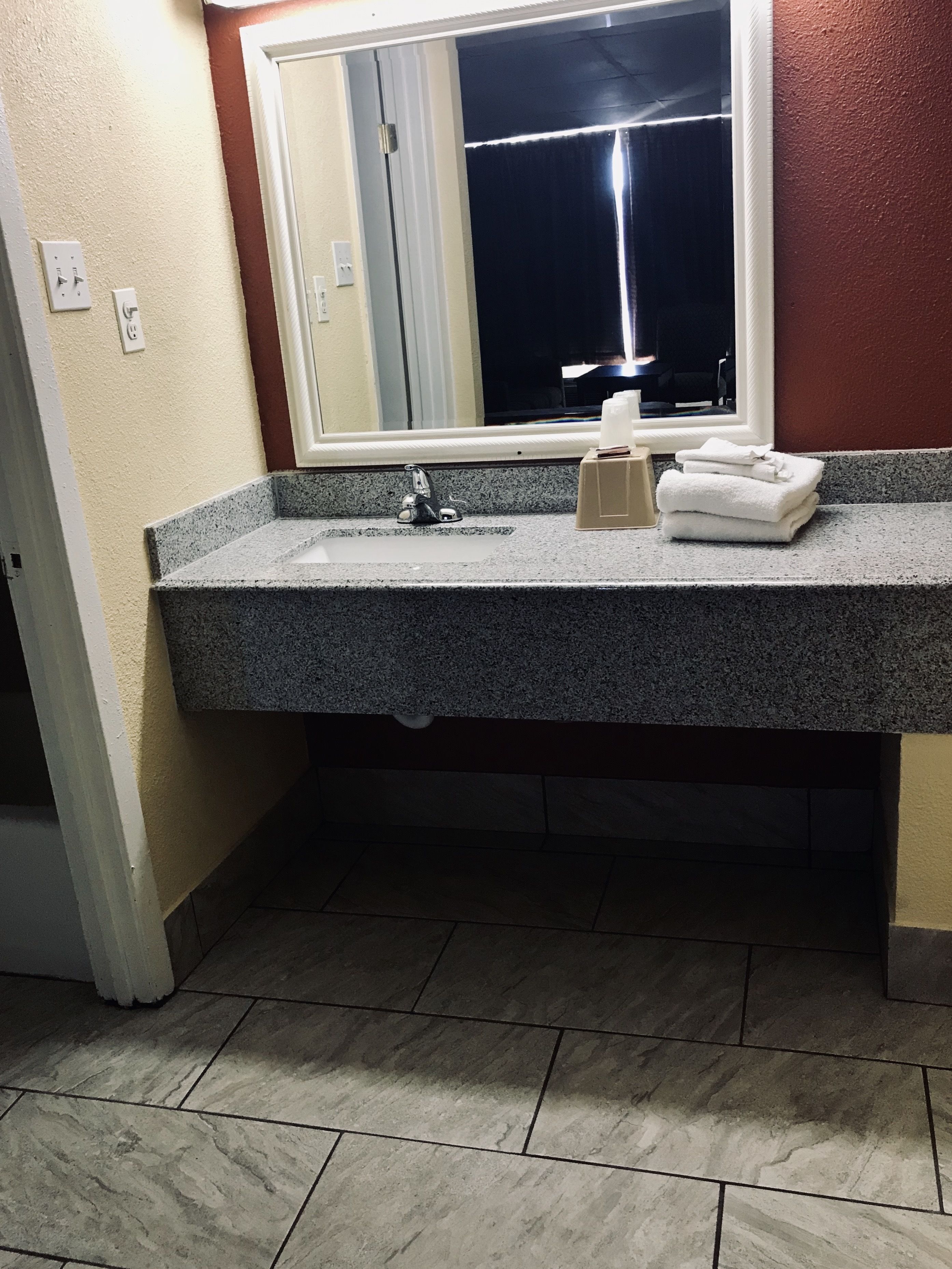 A bathroom with a granite countertop, a sink, a mirror, and a towel rack.
