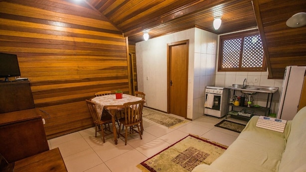 A cozy, compact living space with a dining area, kitchenette, and a sofa. - Apartamento Theobald (Tres Coroas)