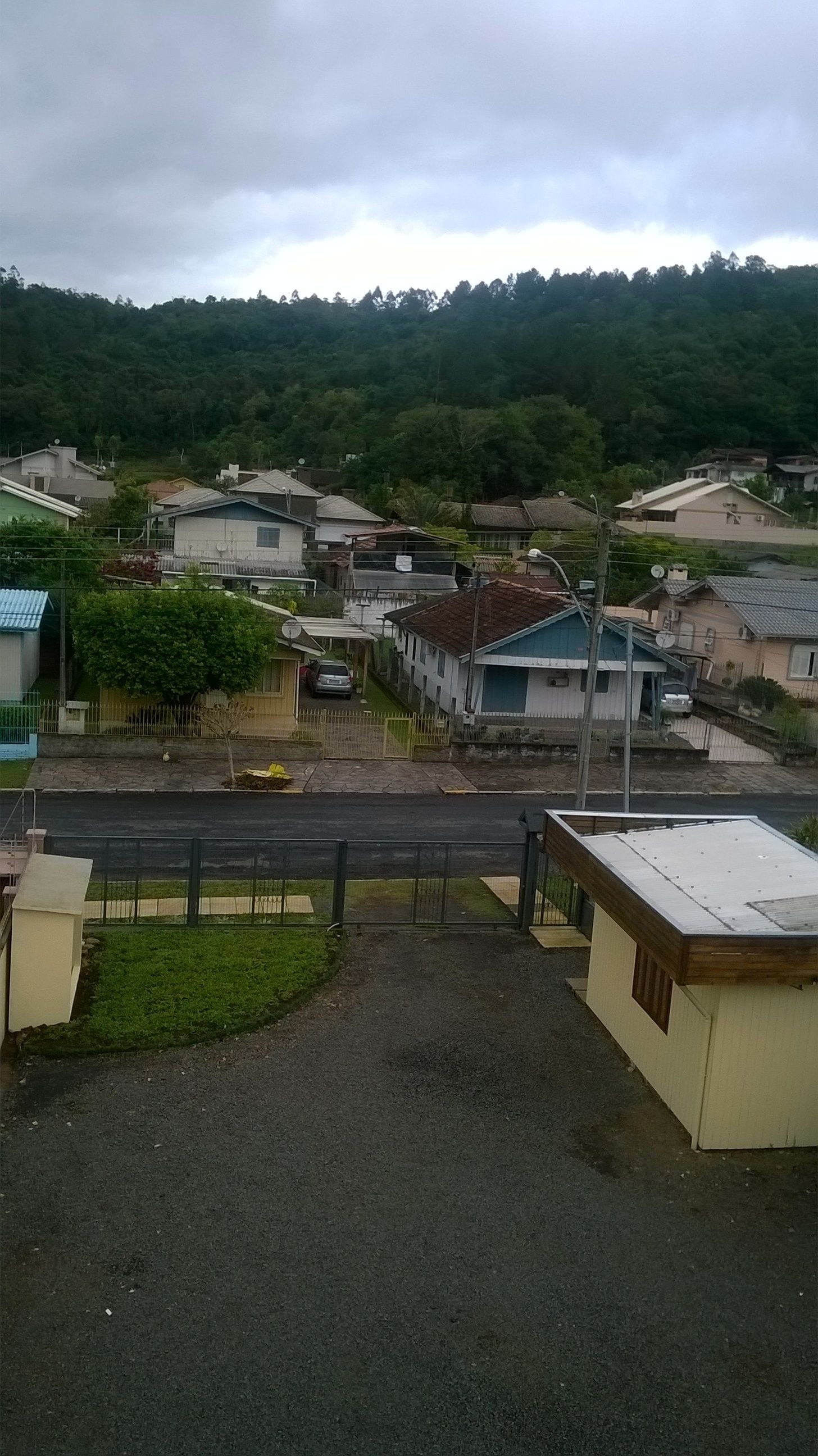 A residential area with houses, a paved road, and a hill in the background.