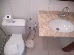 Un baño con inodoro, lavabo y ducha.