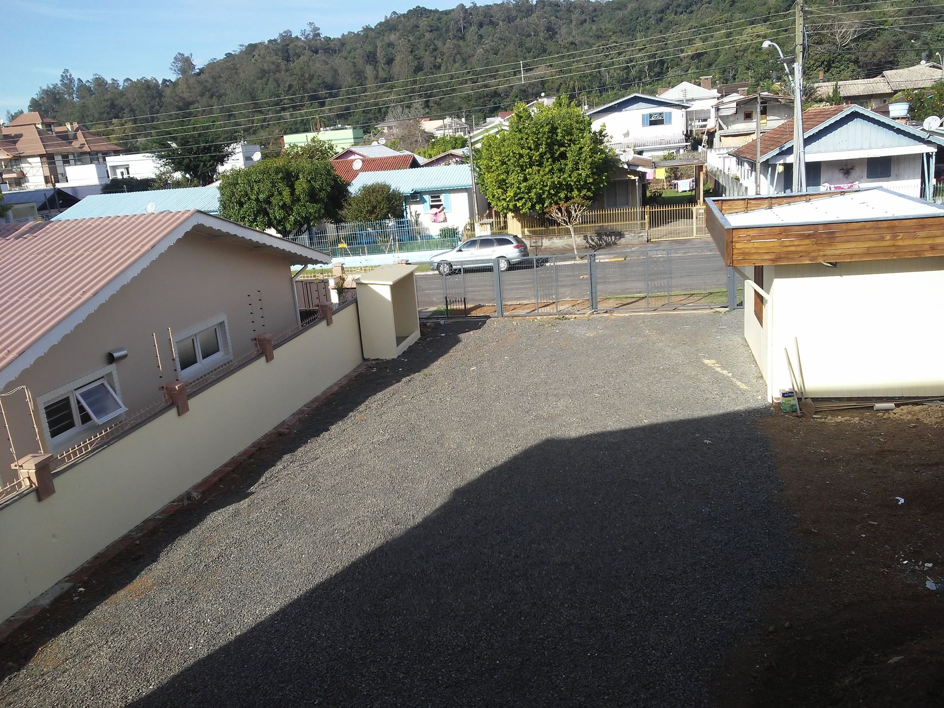 A residential area with houses, a gravel driveway, and a parked car.