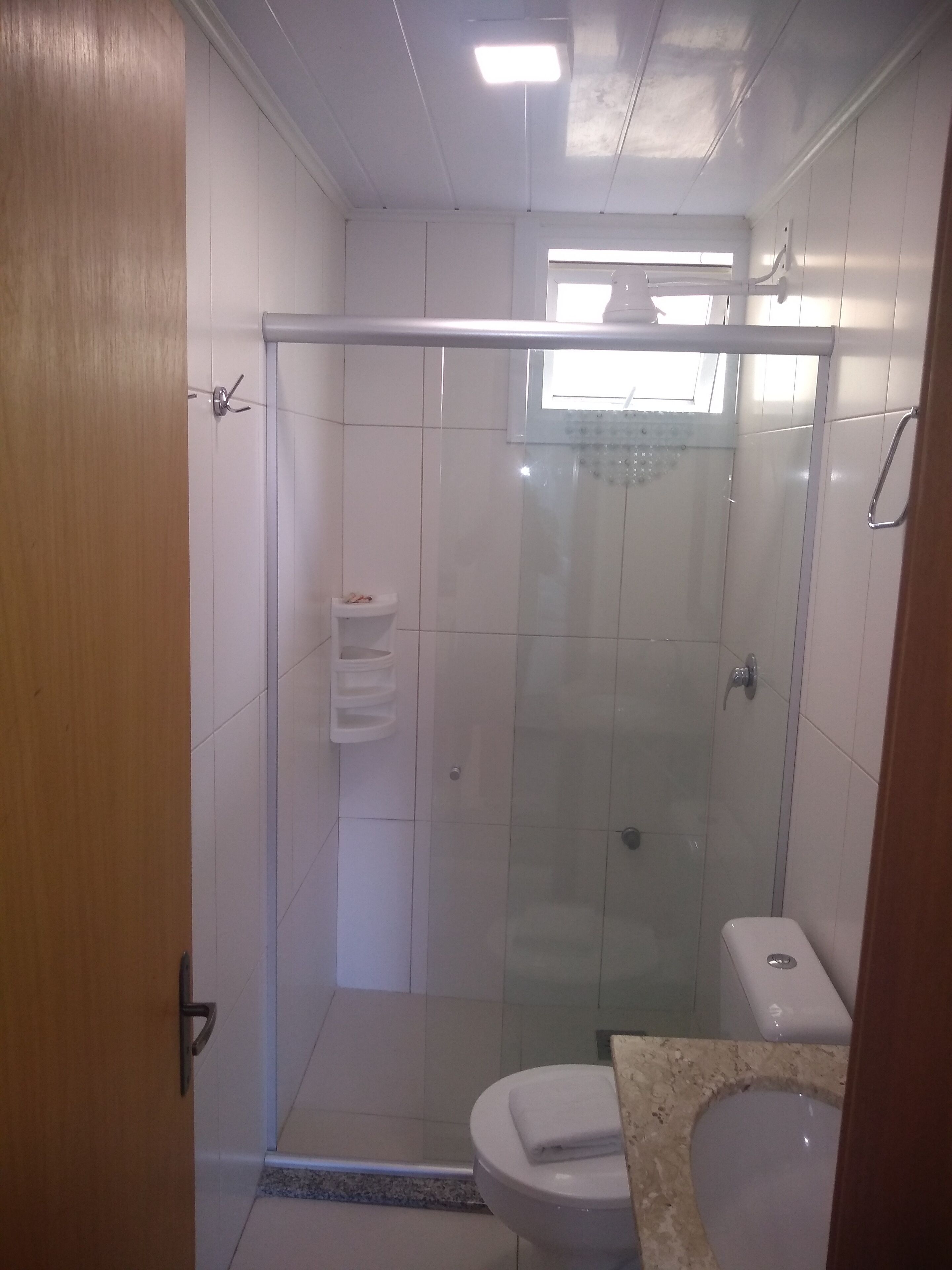 Un baño con ducha de vidrio, inodoro y lavamanos.