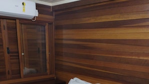 A hotel room with a wooden paneled wall, a bed with white linens, and a beige blanket. - Apartamento Theobald (Tres Coroas)