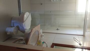 Baño con inodoro, zona de ducha y lavabo.