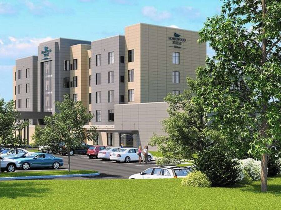 Een modern hotel met meerdere verdiepingen, een parkeerplaats en omliggend groen.