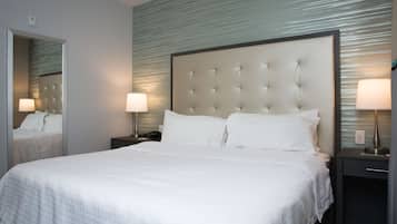 A hotel room with a large bed, two bedside tables with lamps, a mirror, and a textured wall.