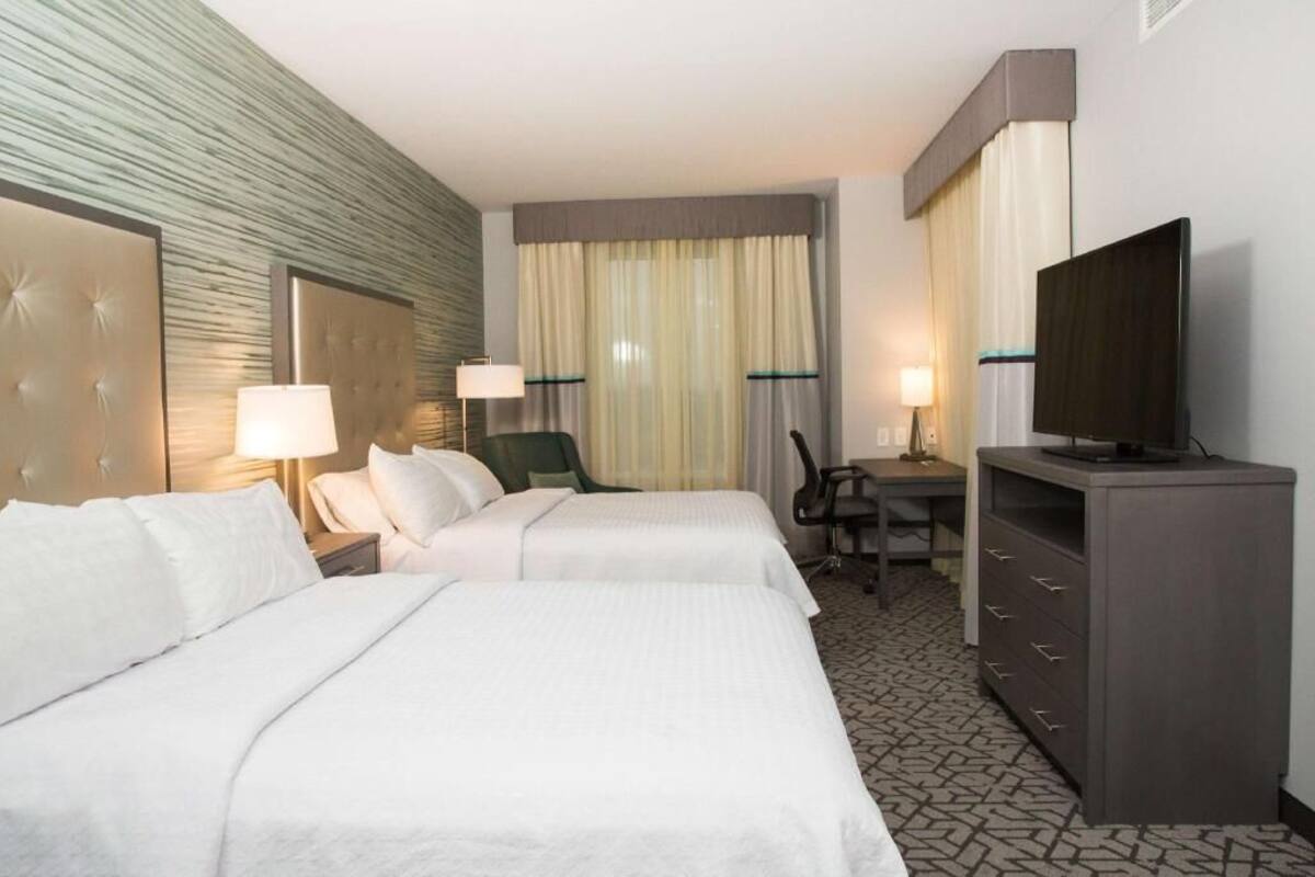 Una habitación de hotel con dos camas, un escritorio, un televisor y una silla.