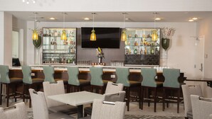 A bar area with multiple seating options, a television, and a variety of bottles and glasses on shelves. - Homewood Suites by Hilton Allentown Bethlehem Center Valley (Center Valley)
