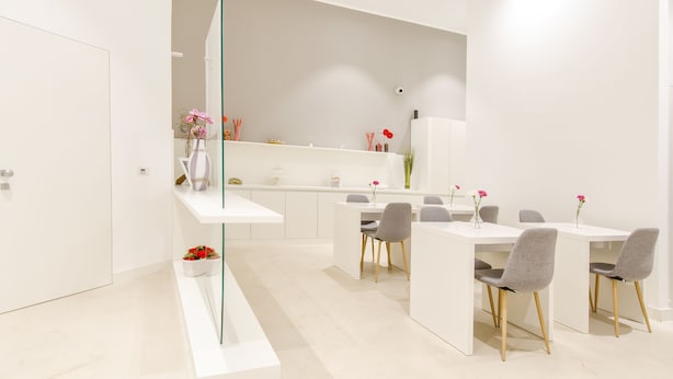 A modern, minimalist dining area with white furniture and a glass partition. - Ortigia Bed and Breakfast (Syracuse)