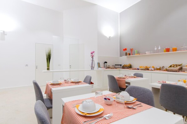 Un comedor moderno con paredes blancas, manteles a cuadros rojos y blancos y sillas grises.