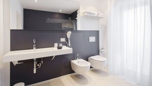 A modern bathroom with a dark wall, white sink, bidet, toilet, and a large mirror. - Ortigia Bed and Breakfast (Syracuse)