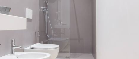 A modern bathroom with a glass-enclosed shower, two sinks, and a toilet.