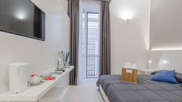 Une chambre d’hôtel moderne équipée d’un lit, d’une table de chevet et d’un téléviseur fixé au mur.