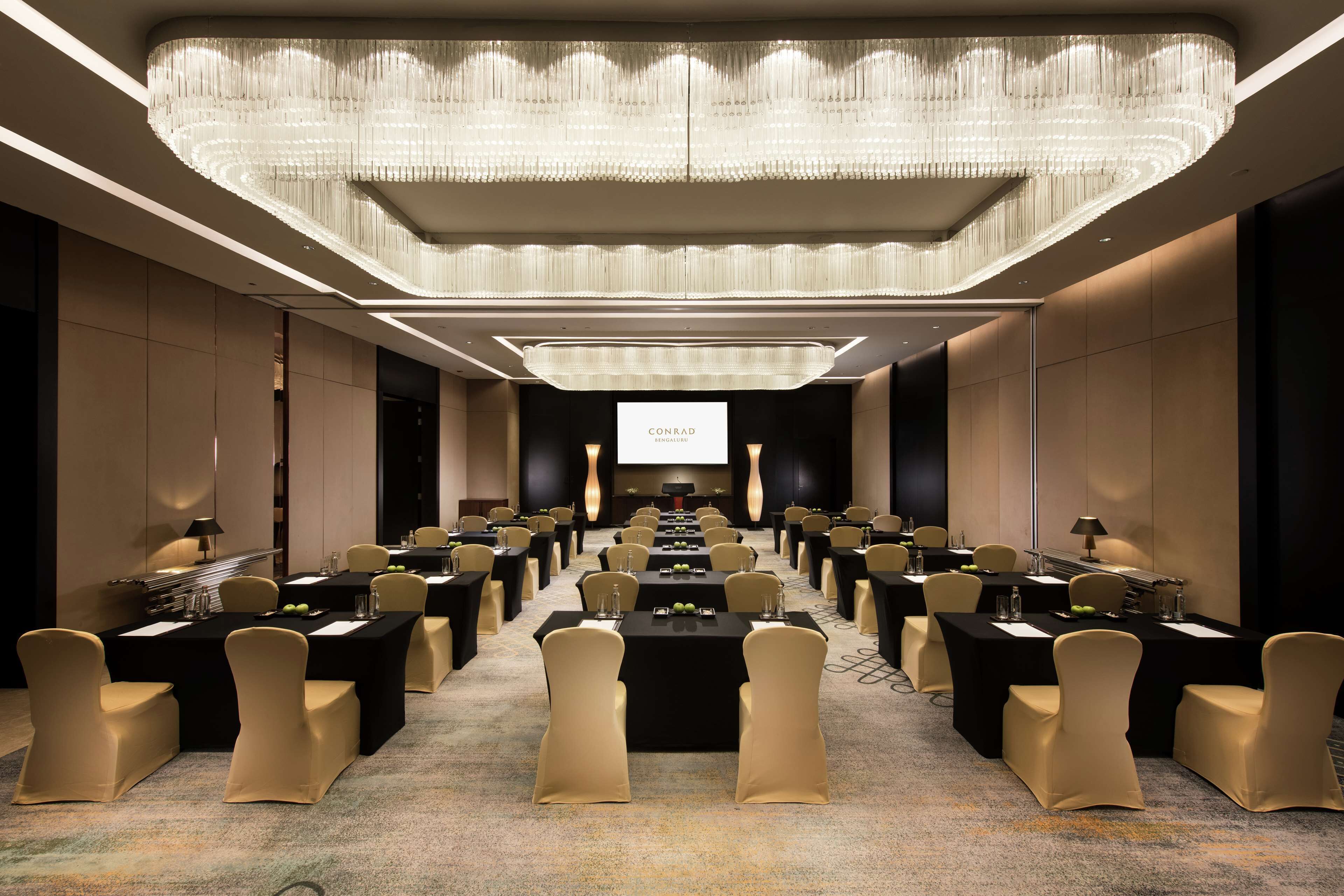 A conference room with a long table, chairs, and a projector screen.