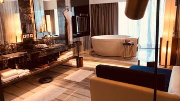 A modern bathroom with a large bathtub, a vanity with a marble countertop, and a large mirror.