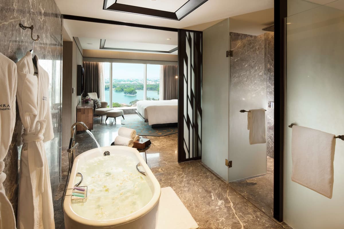Un baño moderno con una bañera grande, ducha y vistas a la ciudad a través de amplias ventanas.