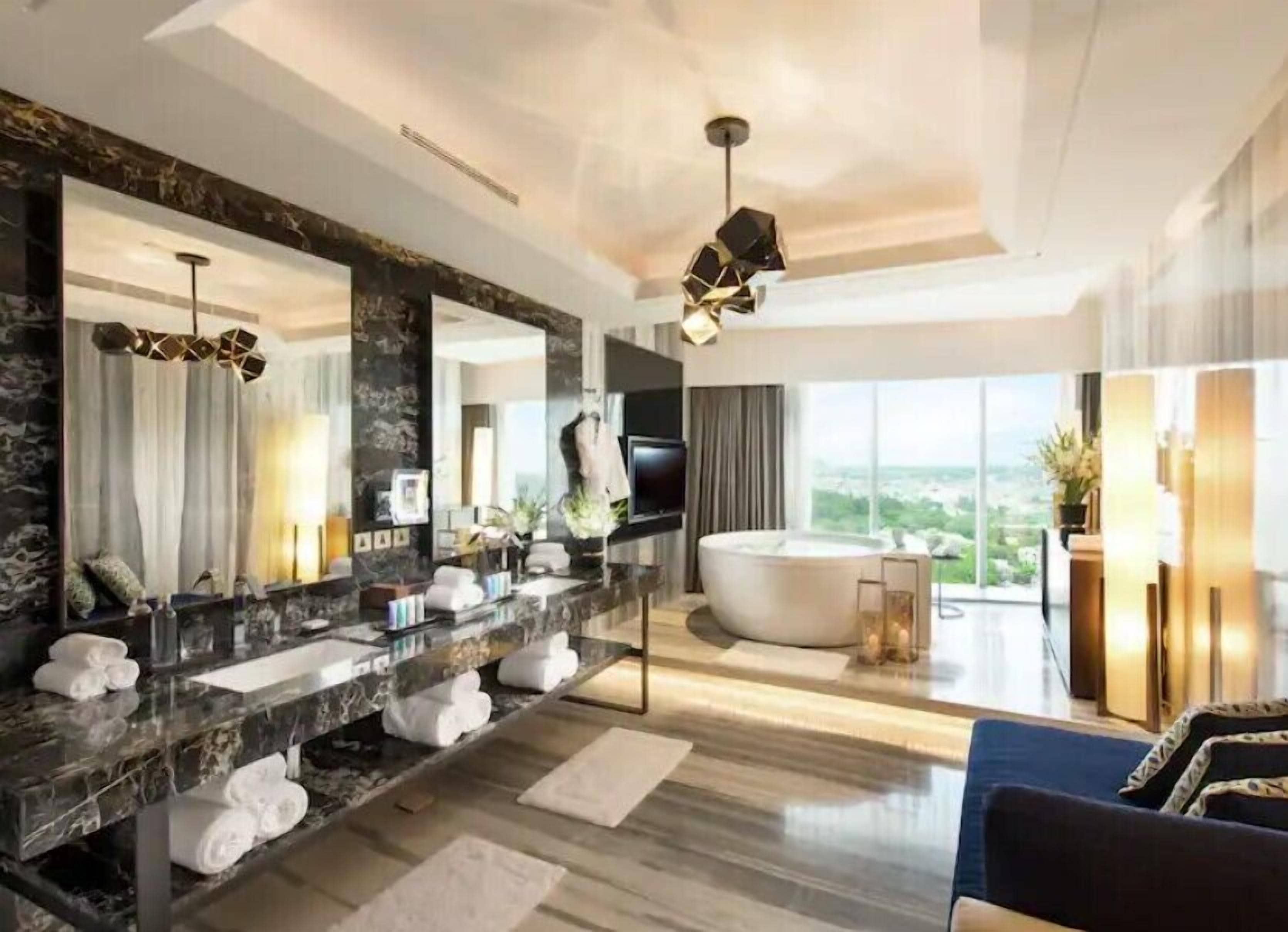 A modern bathroom with a large mirror, a bathtub, and a vanity with towels.