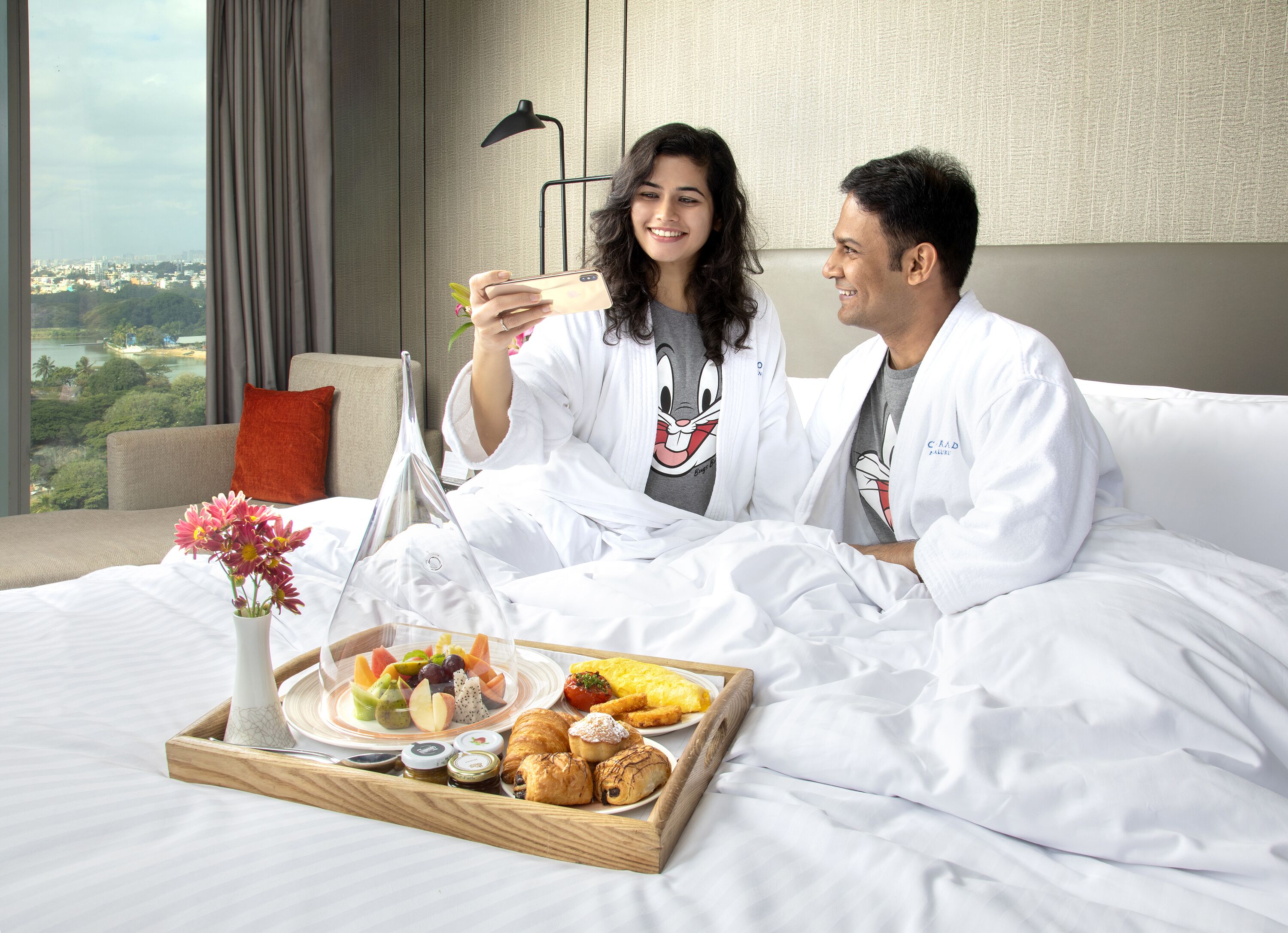 Une chambre d’hôtel avec un lit, un plateau de petit-déjeuner et une vue sur le paysage urbain.