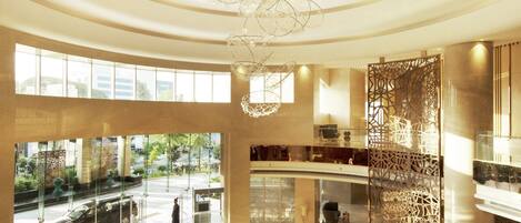 A spacious lobby with a large chandelier, seating area, and a view of the outside.