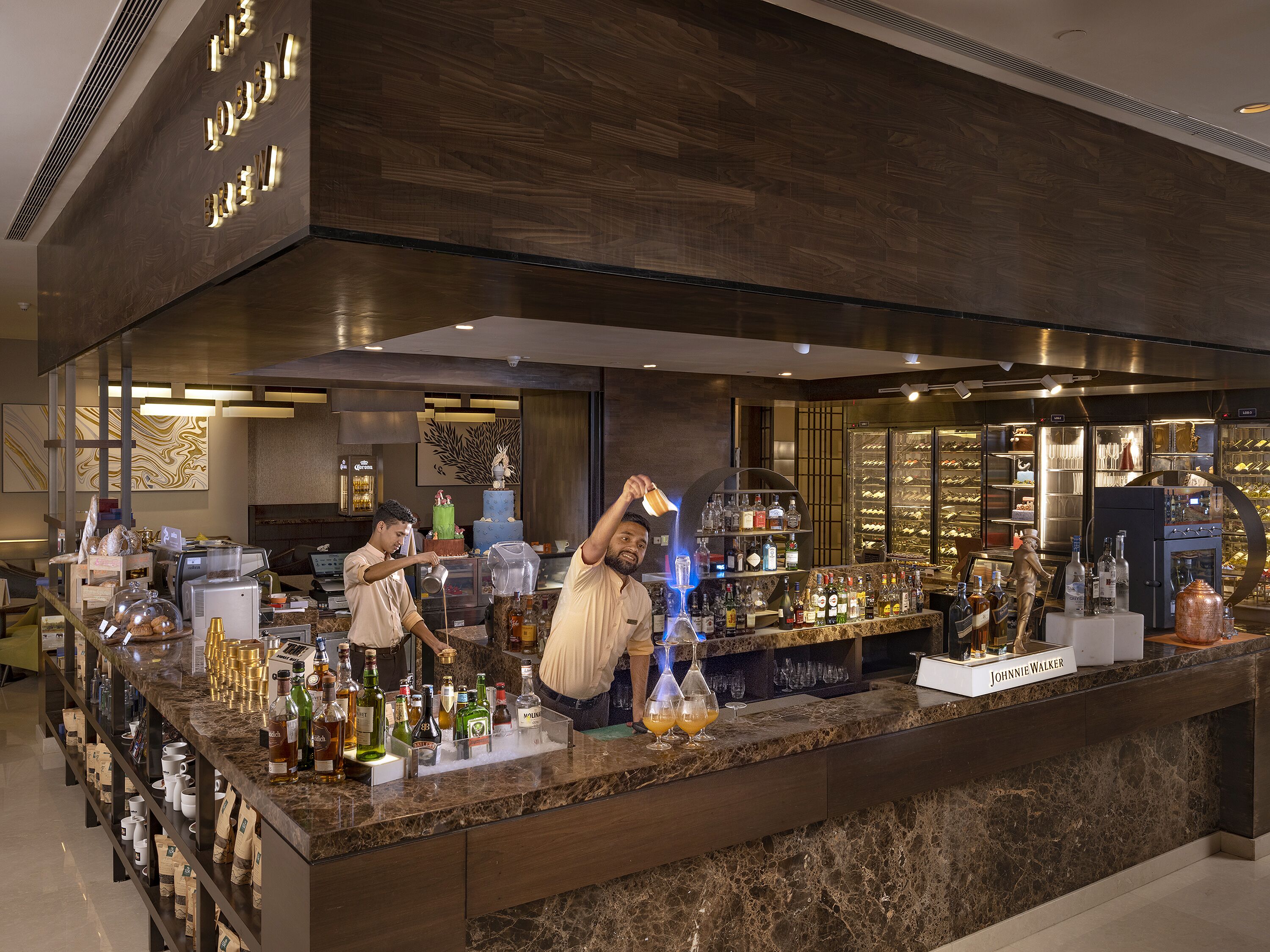 A bar area with a marble countertop, shelves of liquor bottles, and a decorative cake.