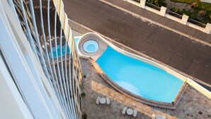 Una piscina en la azotea con un jacuzzi circular, rodeada de sillones de descanso y una pequeña terraza.
