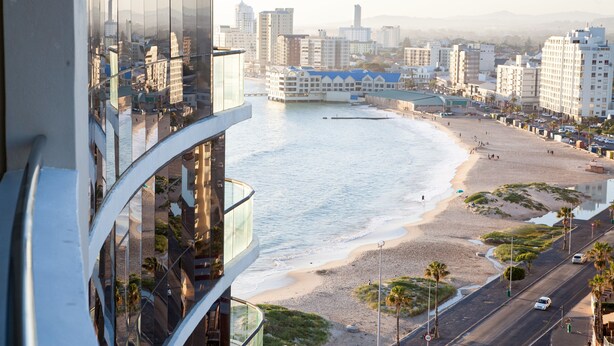 Un paisaje costero con edificios modernos, una playa y una carretera que conduce a la orilla.