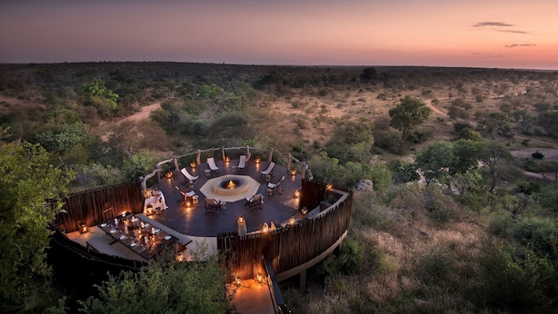 An outdoor circular deck with seating and a central fire pit, surrounded by dense vegetation. - Makumu Private Game Lodge (Bushbuckridge)