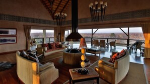 A spacious living room with a large fireplace, comfortable seating, and a view of the landscape. - Makumu Private Game Lodge (Bushbuckridge)