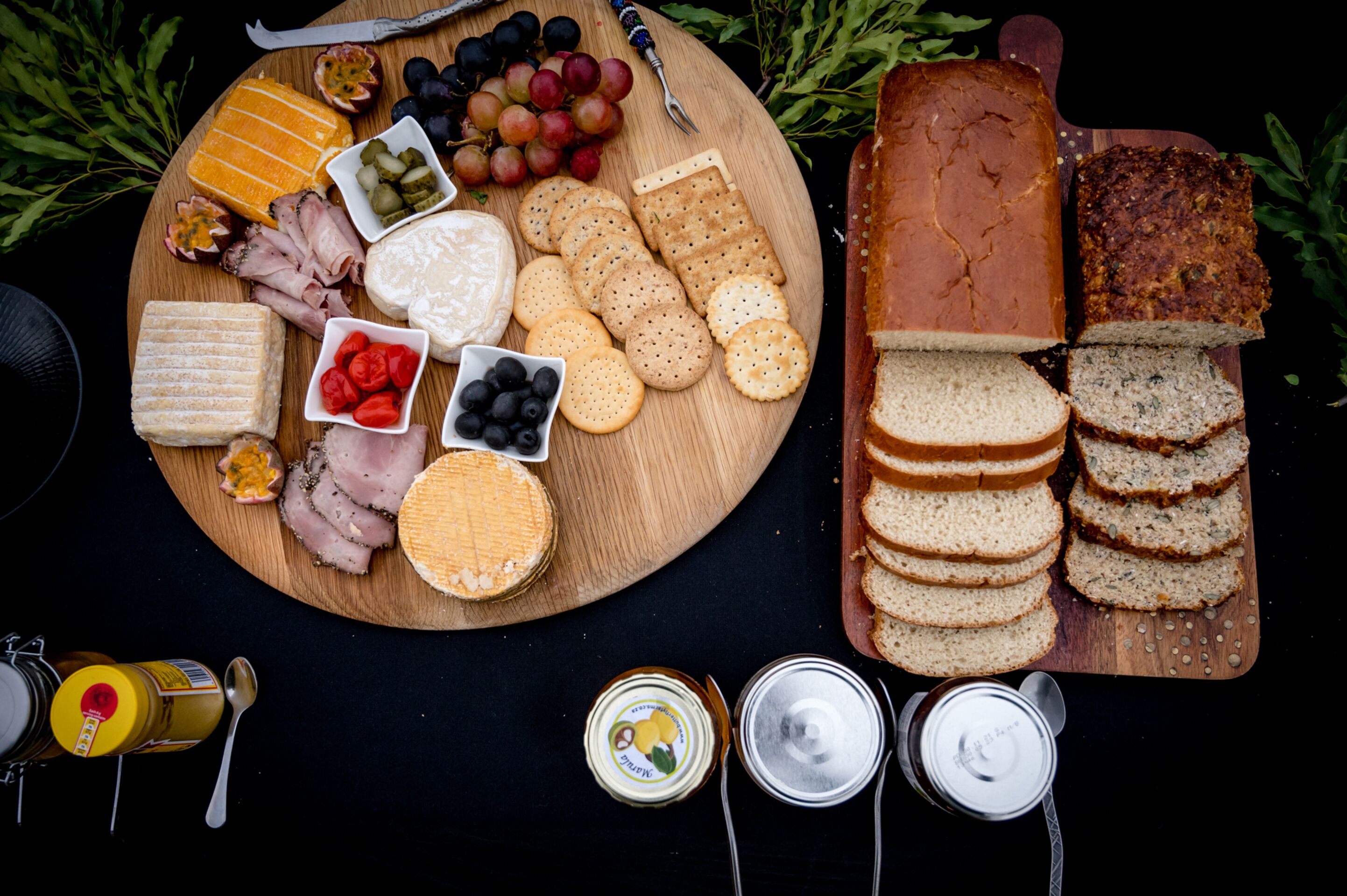 A wooden board with various cheeses, crackers, and sliced bread.